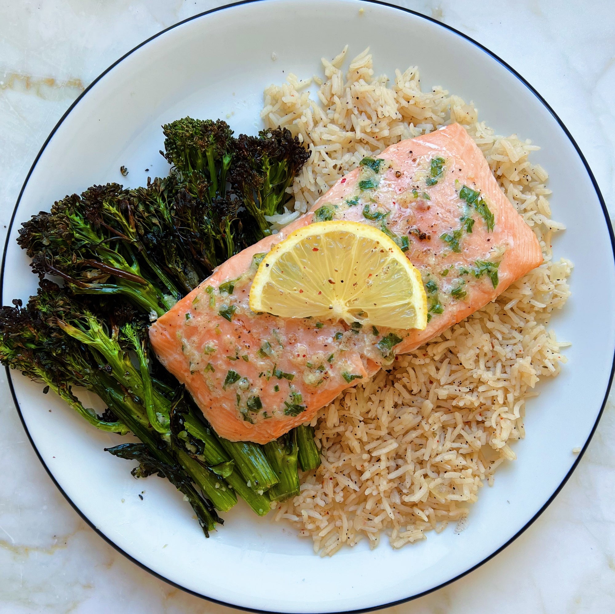 Wild caught Alaskan king salmon grilled on a cedar plank and served on a plate with rice pilaf and roasted broccolini