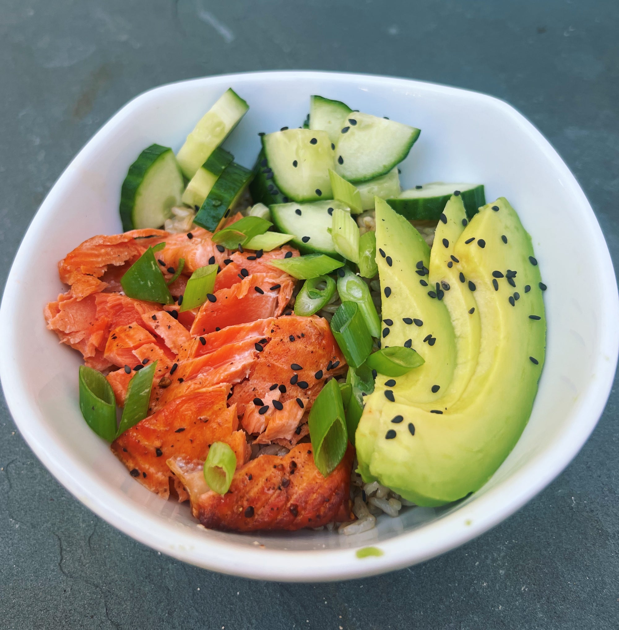 Baked wild-caught salmon served in a bowl of rice, vegetables, and dressing to make a sushi bowl