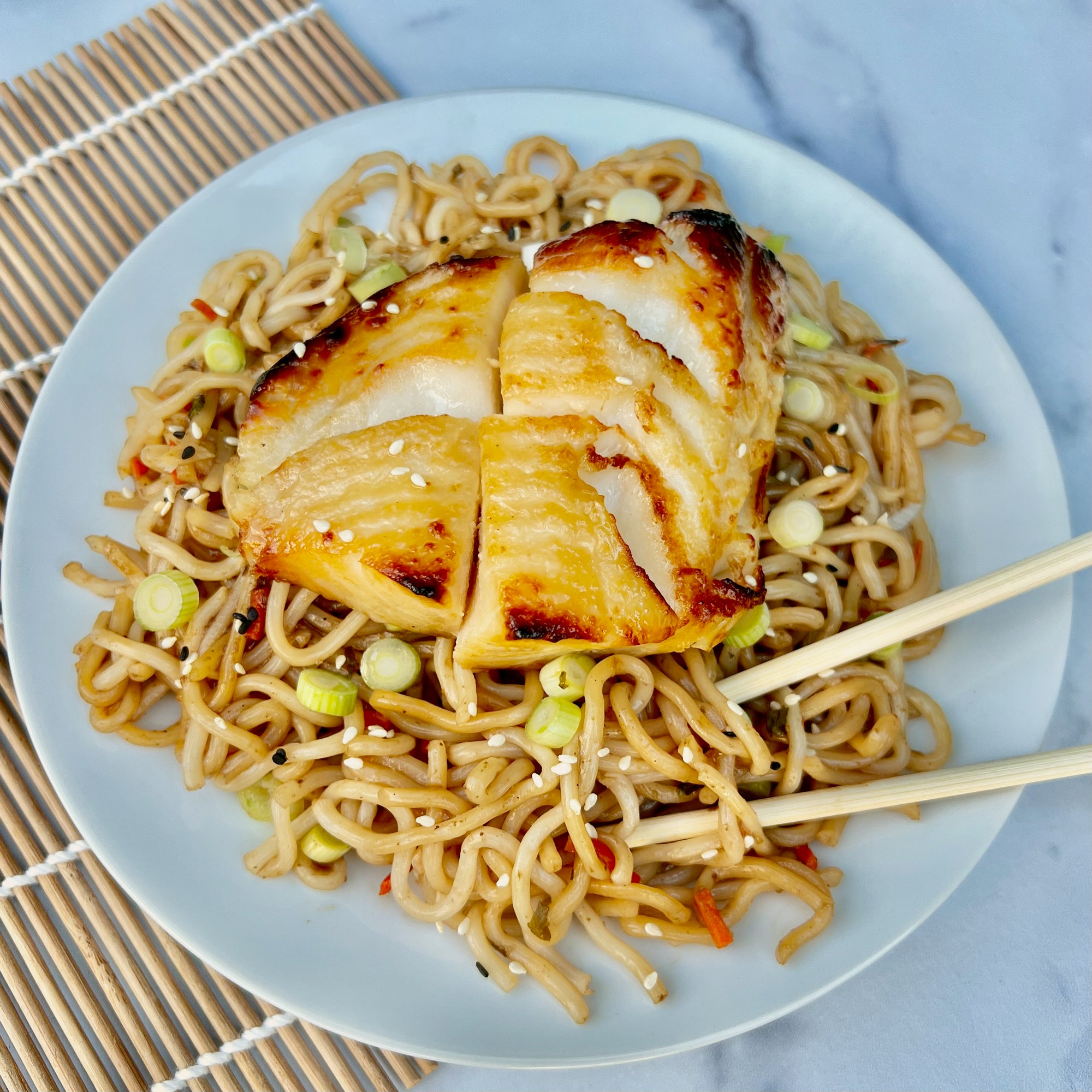 Miso marinated black cod served on a plate with noodles and vegetables